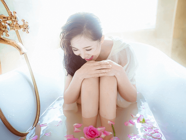浴槽に浮かぶ花びらを見て笑う女性